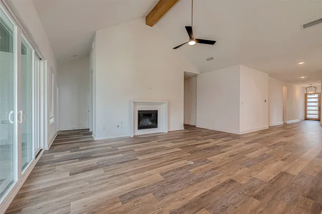 a view of an empty room with wooden floor fireplace and a window