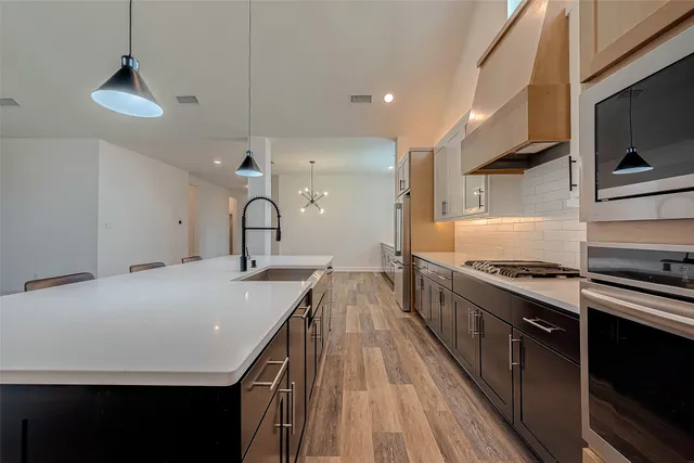 a kitchen with kitchen island a stove a sink and a wooden floor