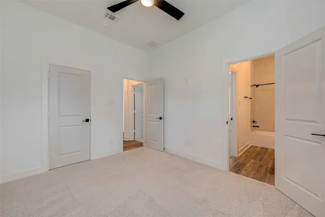 an empty room with closet and a ceiling fan