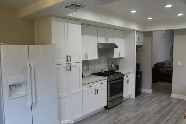 a kitchen with stainless steel appliances granite countertop a refrigerator and a stove top oven
