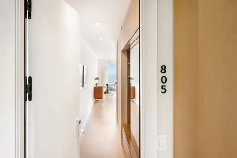 a door with a hallway to the back with wooden floor