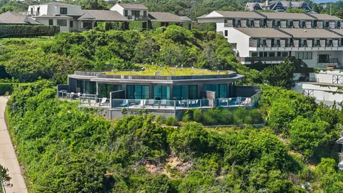 an aerial view of a house with a swimming pool and lawn chairs under large wooden deck