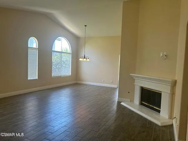 an empty room with wooden floor fireplace and windows