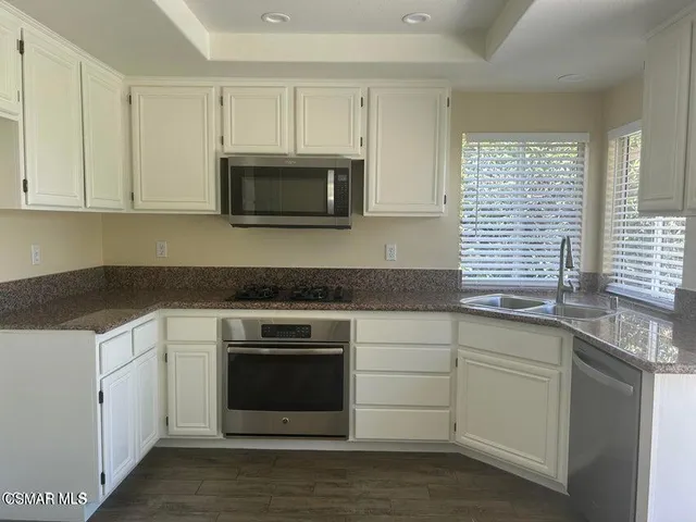 a kitchen with granite countertop white cabinets and a stove