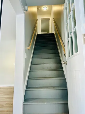 a view of staircase with lots of frames on wall and wooden floor