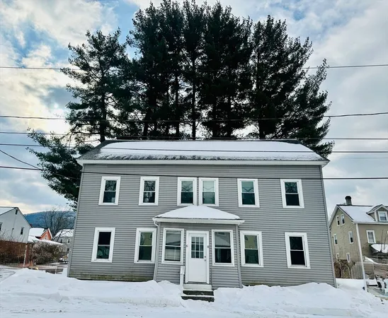 a front view of a house with a tree