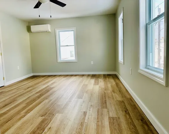a view of empty room with wooden floor and fan