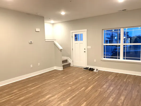 a view of an empty room with window and wooden floor