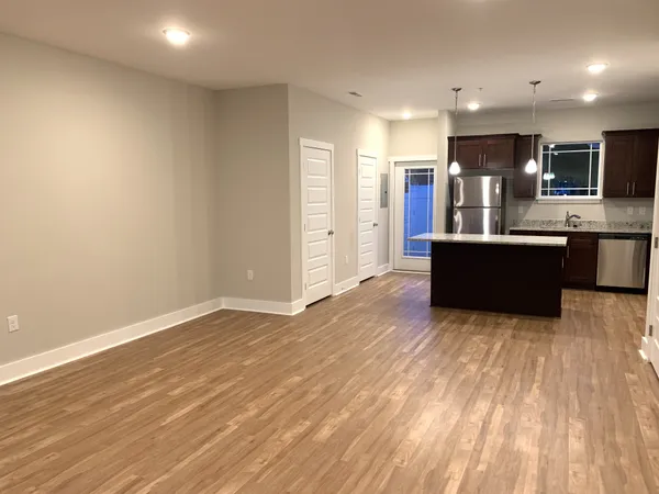 a view of kitchen with kitchen island wooden floor and refrigerator