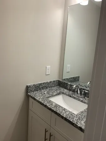 a bathroom with a granite countertop sink and a mirror