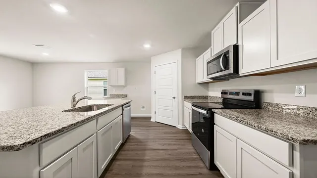 a kitchen with stainless steel appliances granite countertop a sink and dishwasher a stove top oven with wooden floor