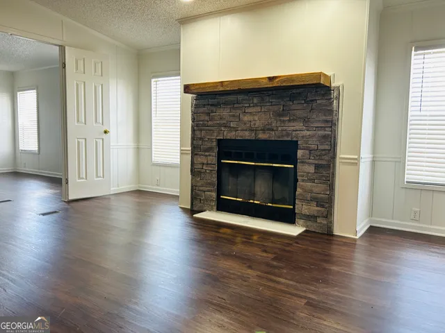 an empty room with wooden floor fireplace and windows