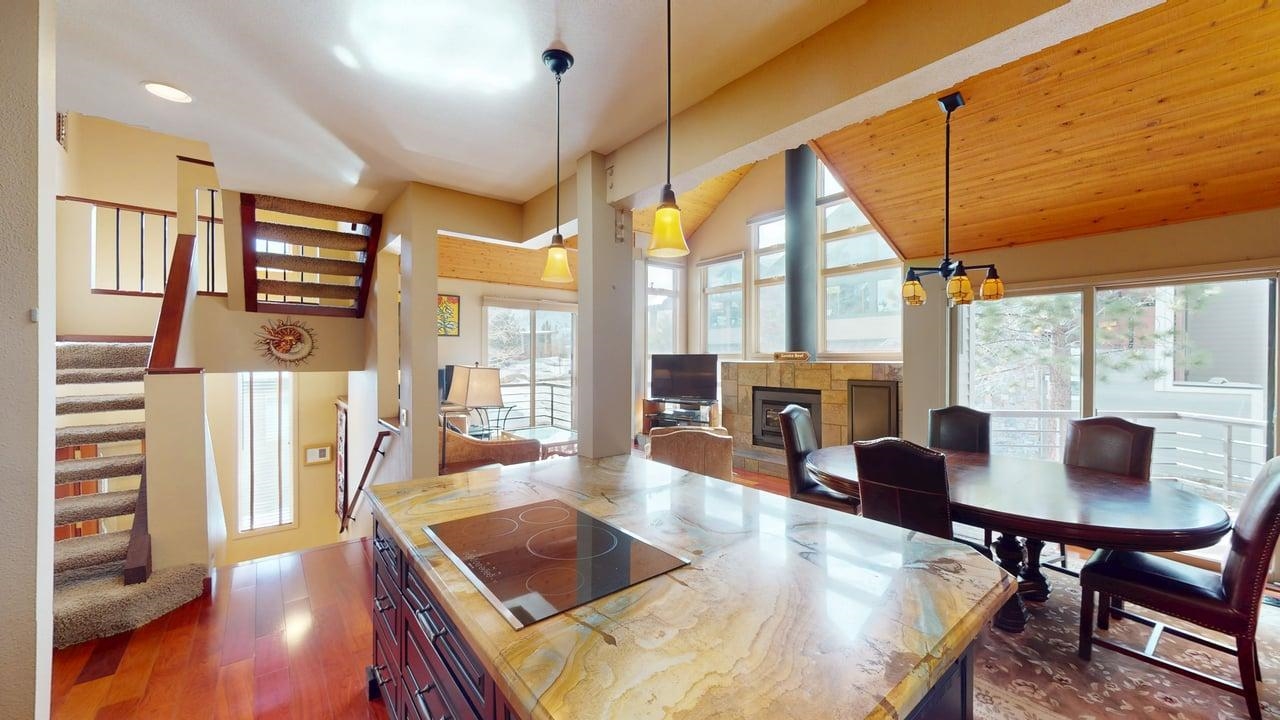 3600 Chateau Road, Unit 2 Mammoth Lakes, CA 93546 - Photo 1 of 30 Dining space featuring dark wood-style floors, a tiled fireplace, stairs, and a chandelier