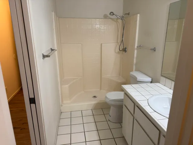 a bathroom with a granite countertop sink toilet and shower