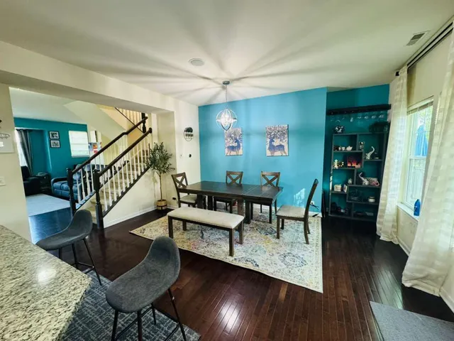a living room with couches and a dining table with wooden floor
