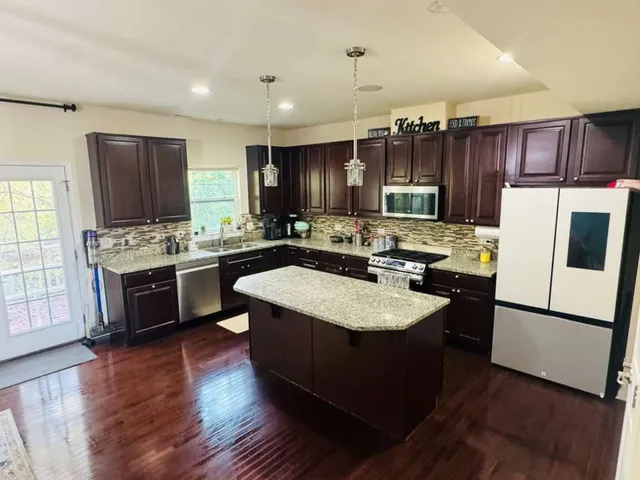 a kitchen with kitchen island stainless steel appliances a sink a stove a refrigerator cabinets and a center island