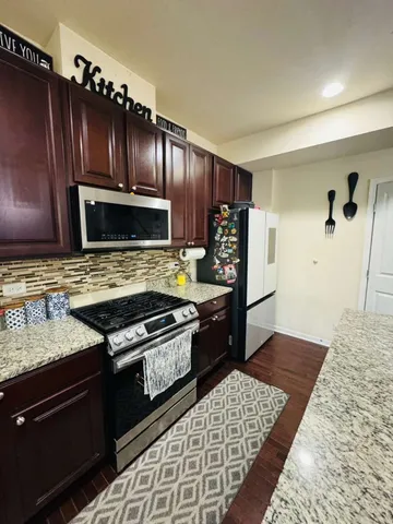 a kitchen with granite countertop wooden cabinets and stainless steel appliances
