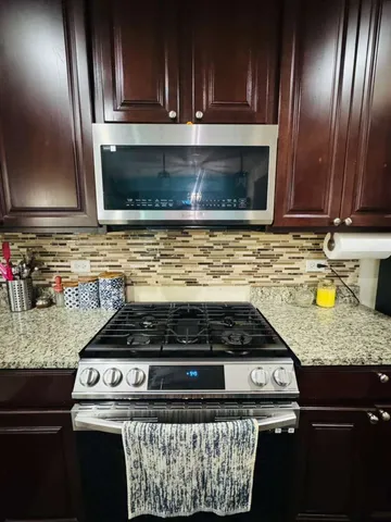 a kitchen with granite countertop stainless steel appliances a stove microwave and sink