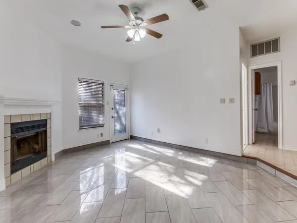 a view of a livingroom with a fireplace a ceiling fan and window