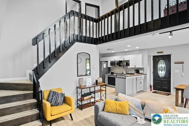 a living room with furniture kitchen view and a wooden floor