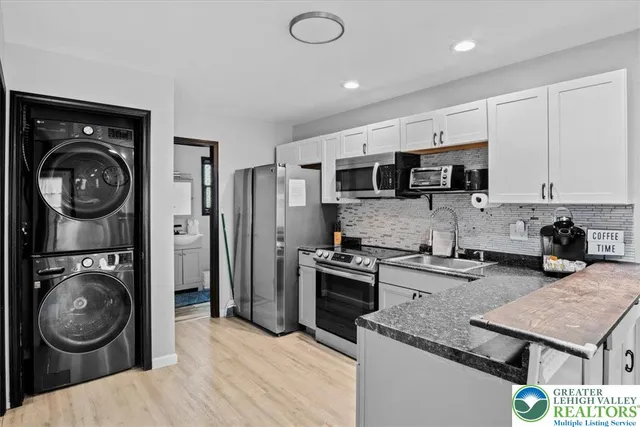 a kitchen with stainless steel appliances granite countertop a sink a stove a washer and dryer