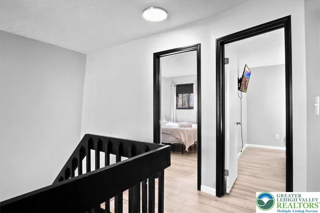 a view of a hallway to a livingroom with wooden floor and furniture