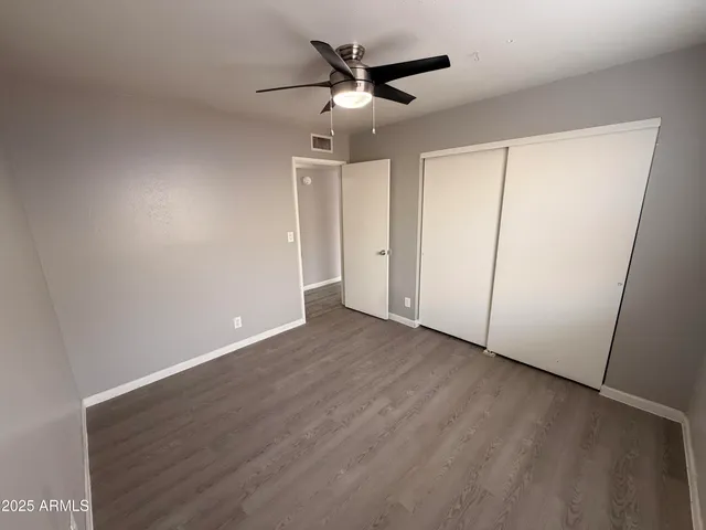 an empty room with wooden floor and ceiling fan