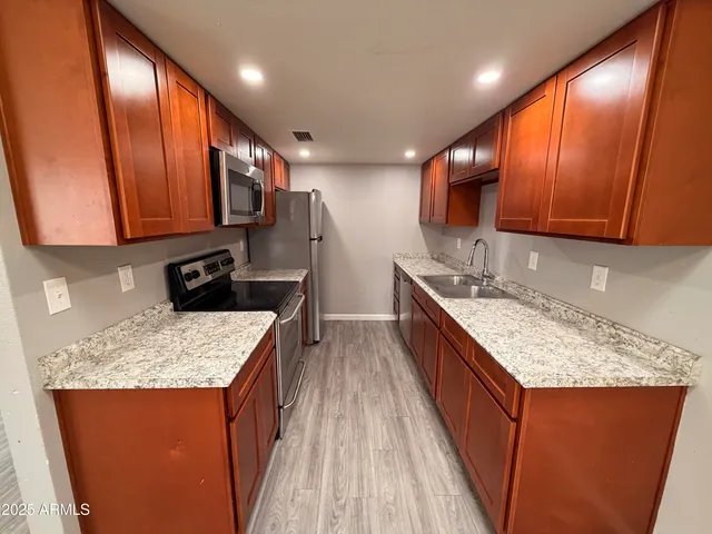 a kitchen with stainless steel appliances granite countertop wooden cabinets a sink and a stove