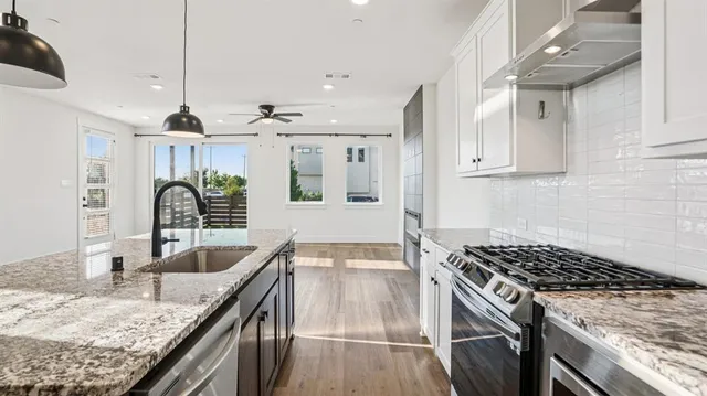 a kitchen with granite countertop a sink stove and cabinets