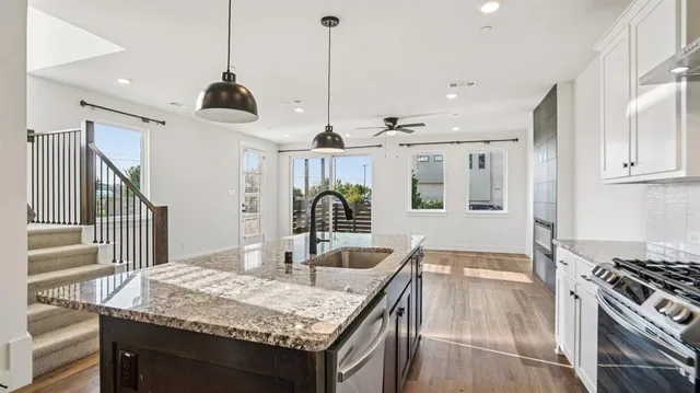 a kitchen with granite countertop a sink a stove and cabinets