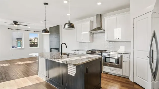 a kitchen with kitchen island granite countertop a stove a sink a dining table and chairs with wooden floor