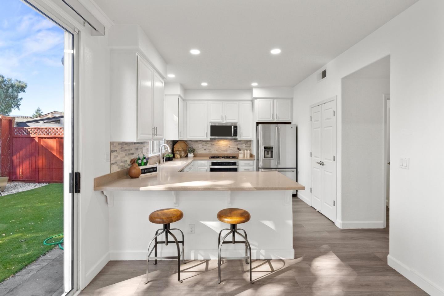 4675 La Crescent Loop San Jose, CA 95136 - Photo 7 of 22 a kitchen with stainless steel appliances granite countertop a stove a refrigerator a microwave oven a sink with island chairs and wooden floor