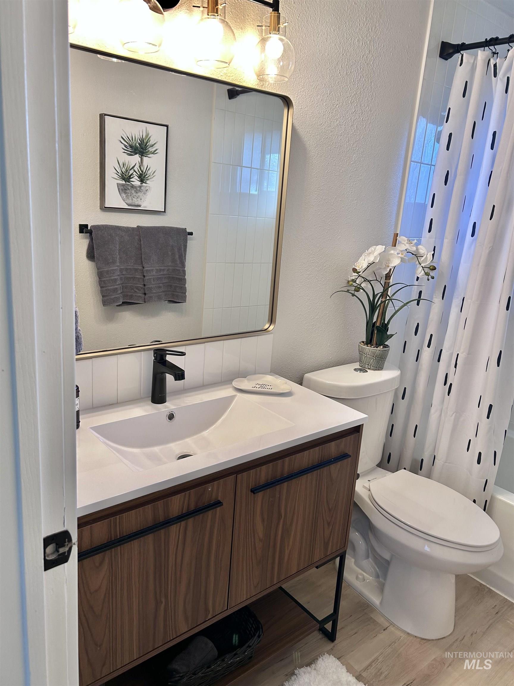 3897 South Yorktown Way Boise, ID 83706 - Photo 12 of 23 Bathroom featuring a textured wall, vanity, light wood-style flooring, and shower / bath combination with curtain