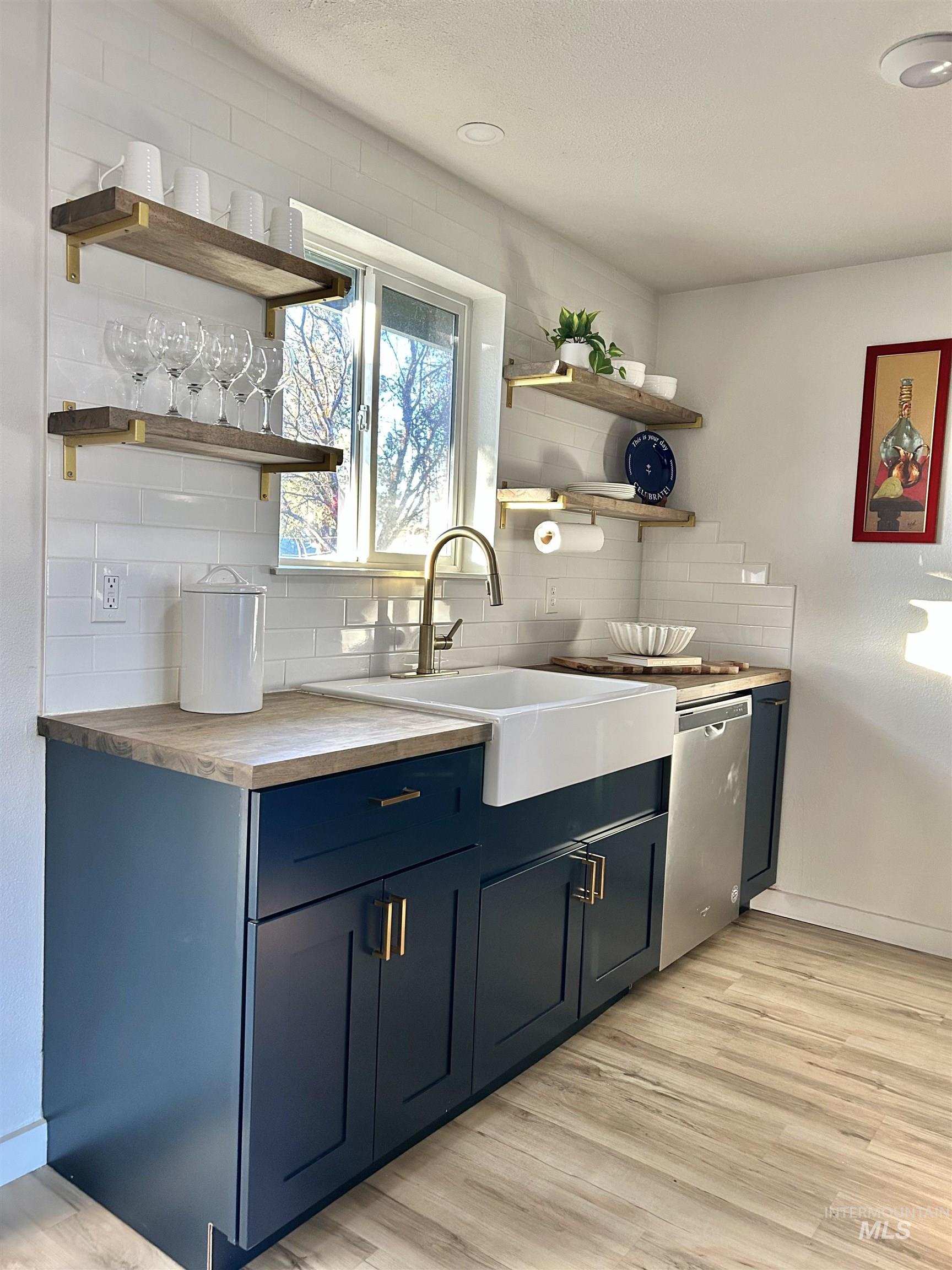 3897 South Yorktown Way Boise, ID 83706 - Photo 8 of 23 Kitchen with open shelves, blue cabinetry, tasteful backsplash, light wood finished floors, and stainless steel dishwasher