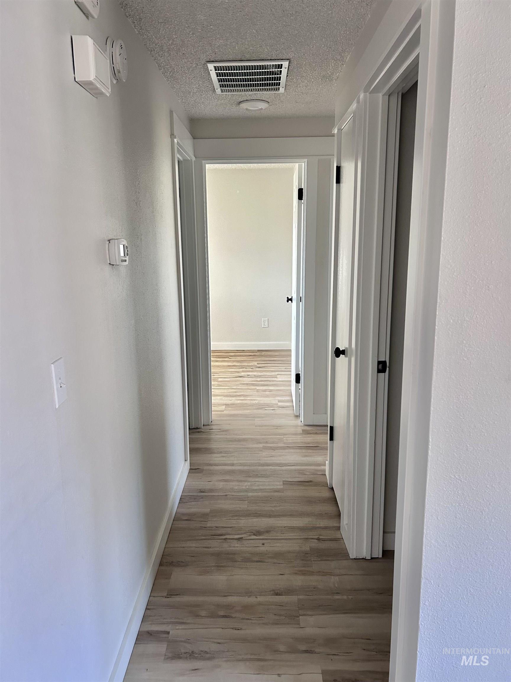 3897 South Yorktown Way Boise, ID 83706 - Photo 10 of 23 Corridor with light wood finished floors, a textured ceiling, and a textured wall