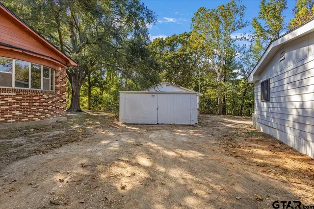 a backyard of a house with large trees and wooden fence