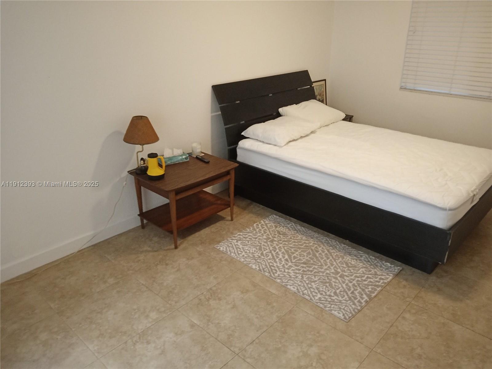 1906 Tigertail Avenue Miami, FL 33133 - Photo 8 of 17 a bed sitting in a bedroom next to a window