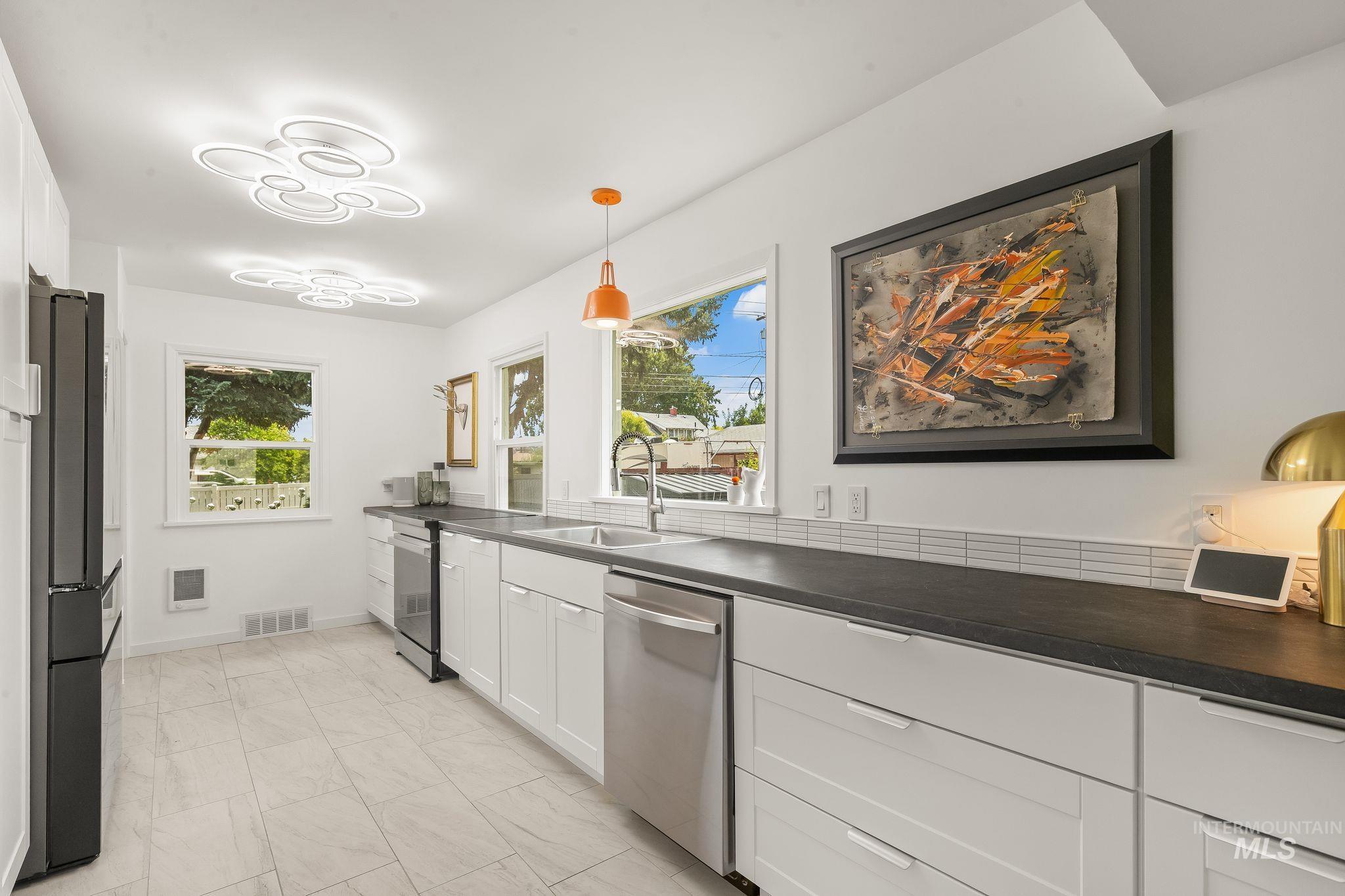 1315 8th Street Clarkston, WA 99403 - Photo 13 of 37 Modern kitchen featuring white cabinetry, dark countertops, a subway tile backsplash, and stainless-steel appliances