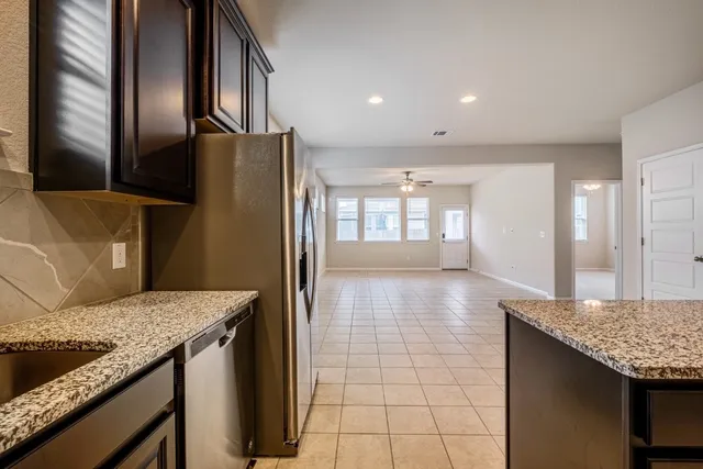 a kitchen with stainless steel appliances granite countertop a sink a refrigerator and a stove