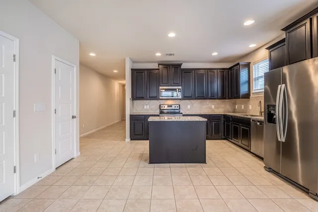a kitchen with kitchen island granite countertop wooden cabinets and stainless steel appliances