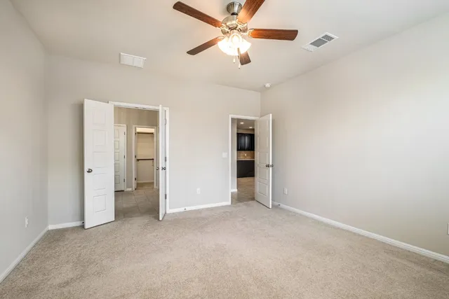an empty room with closet and a ceiling fan