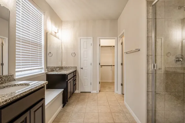 a spacious bathroom with a granite countertop sink a mirror and a shower