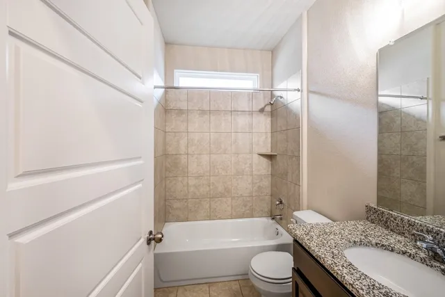 a bathroom with a granite countertop bathtub shower sink vanity and toilet