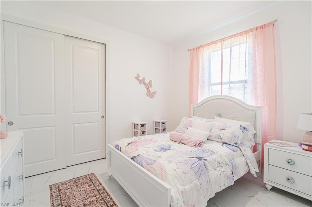 907 Homestead Road South Lehigh Acres, FL 33974 - Photo 20 of 43 Room featuring white walls, white panel sliding closet doors, a window, and light-toned flooring