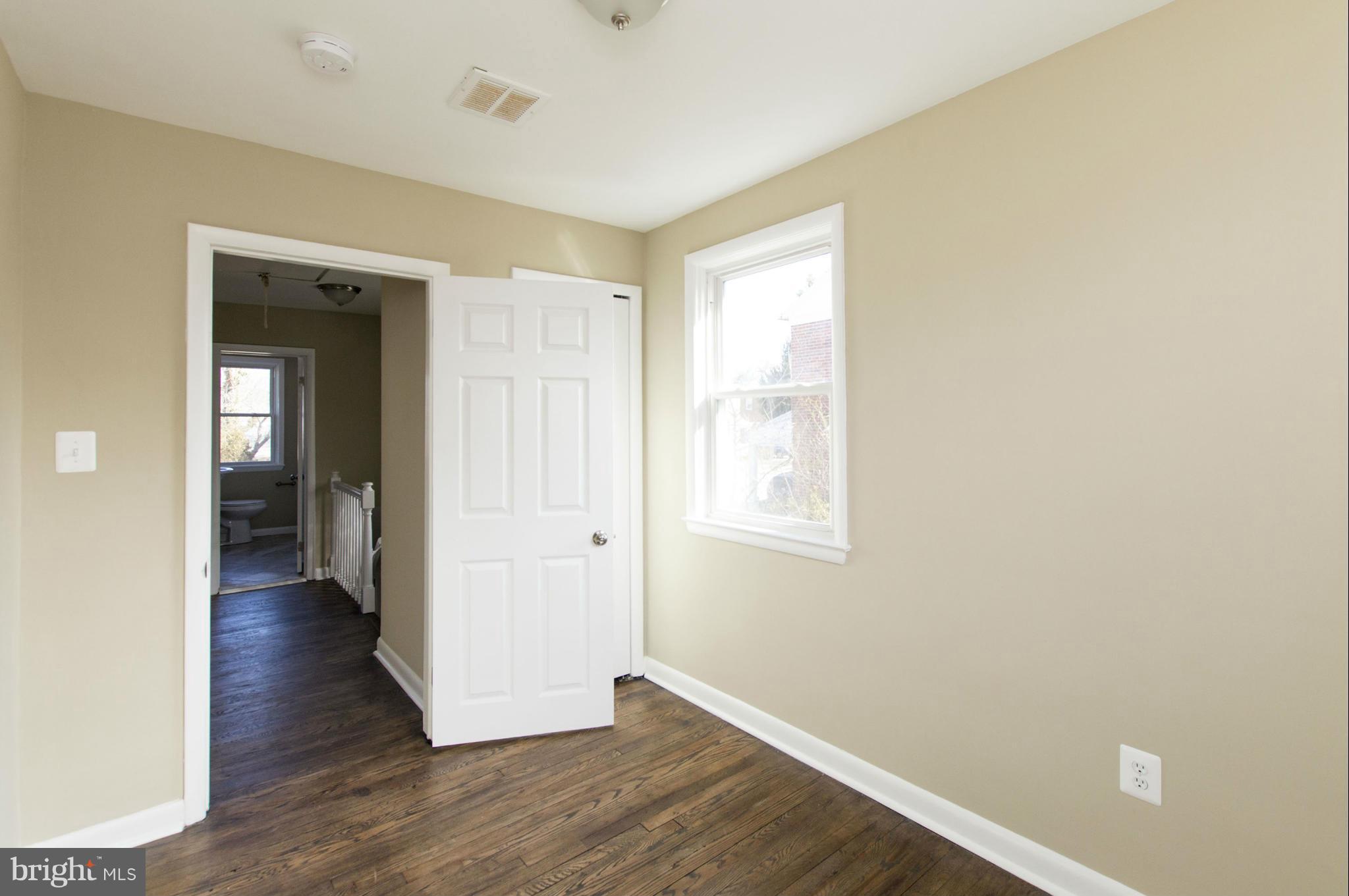 1111 Hollen Road Baltimore, MD 21239 - Photo 17 of 30 an empty room with wooden floor and windows