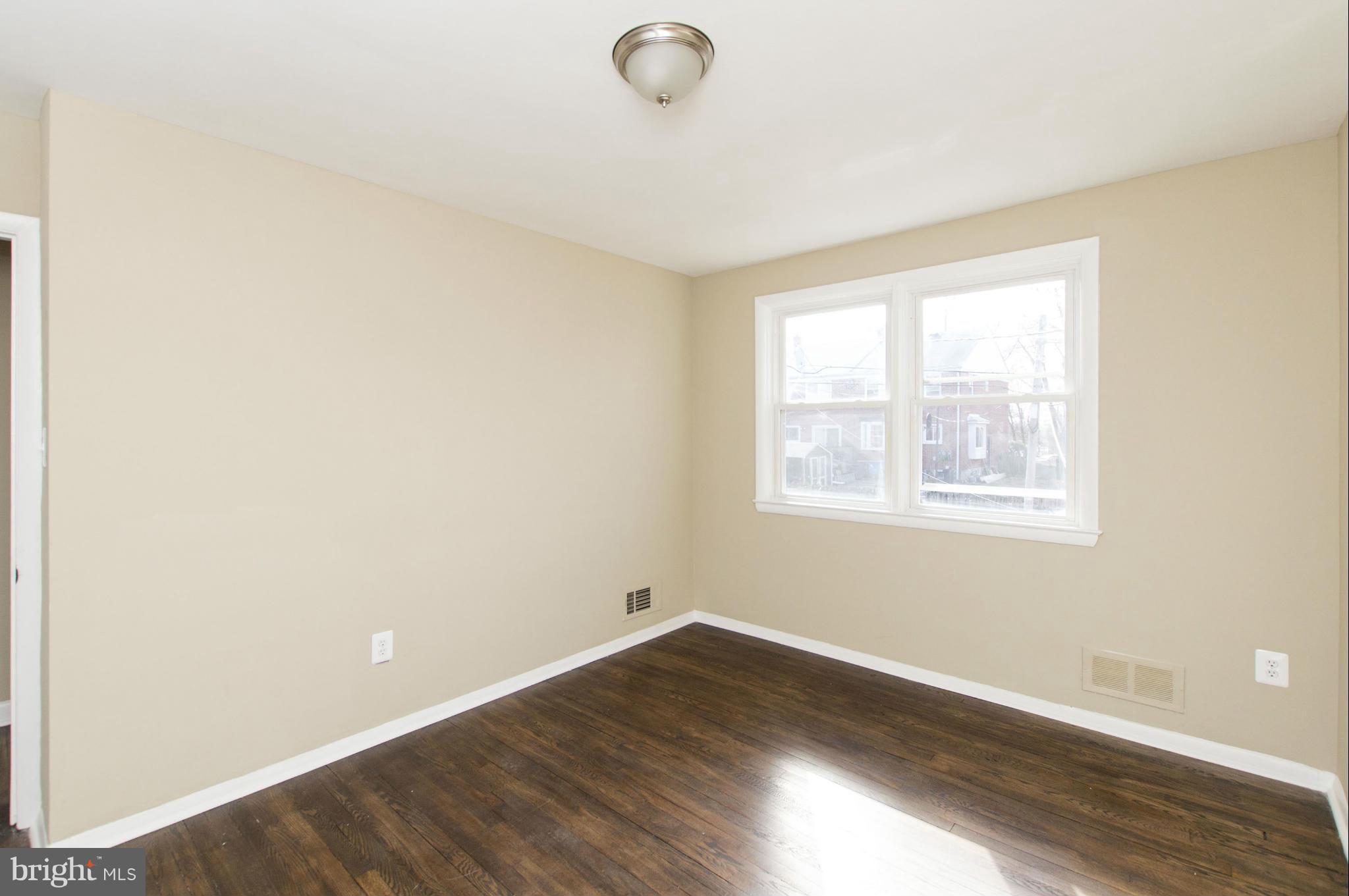 1111 Hollen Road Baltimore, MD 21239 - Photo 18 of 30 an empty room with wooden floor and windows