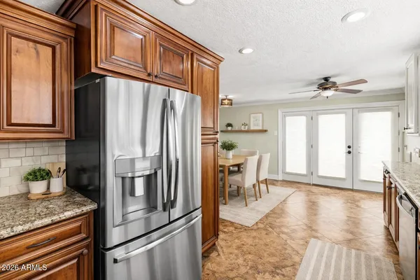 a kitchen with stainless steel appliances granite countertop a refrigerator oven stove a dining table and chairs with wooden floor