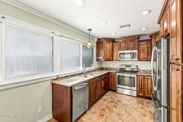 a kitchen with stainless steel appliances granite countertop a stove top oven sink and refrigerator