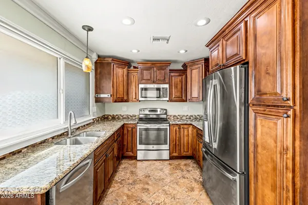a kitchen with stainless steel appliances granite countertop a refrigerator a stove and a sink