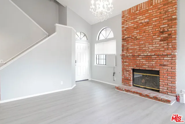a view of an empty room with wooden floor and a fireplace